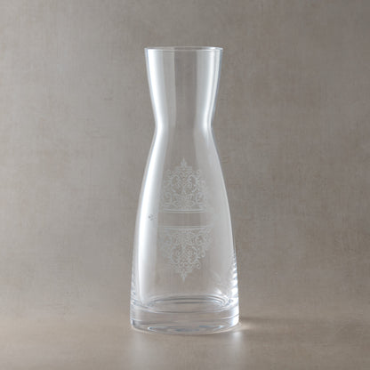 Glass carafe engraved with a Guipure lace design, photographed on a beige background
