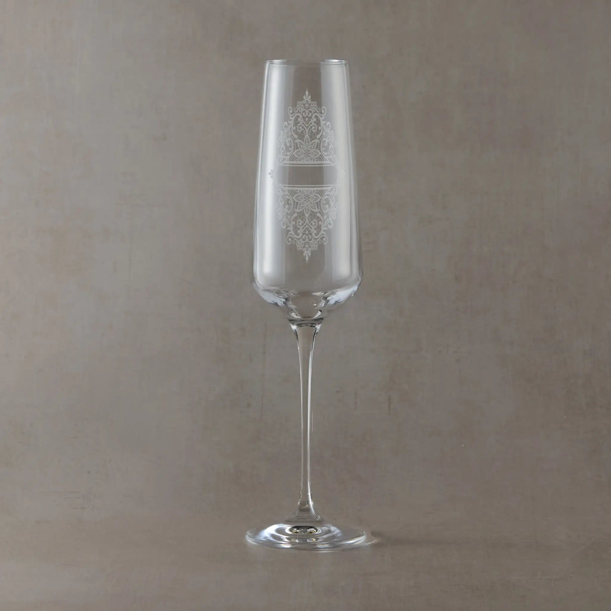 Tall champagne flute engraved with Guipure lace design, photographed on a light neutral background