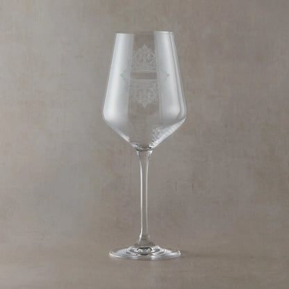 Clear wine glass with an engraved lacework design on a beige background