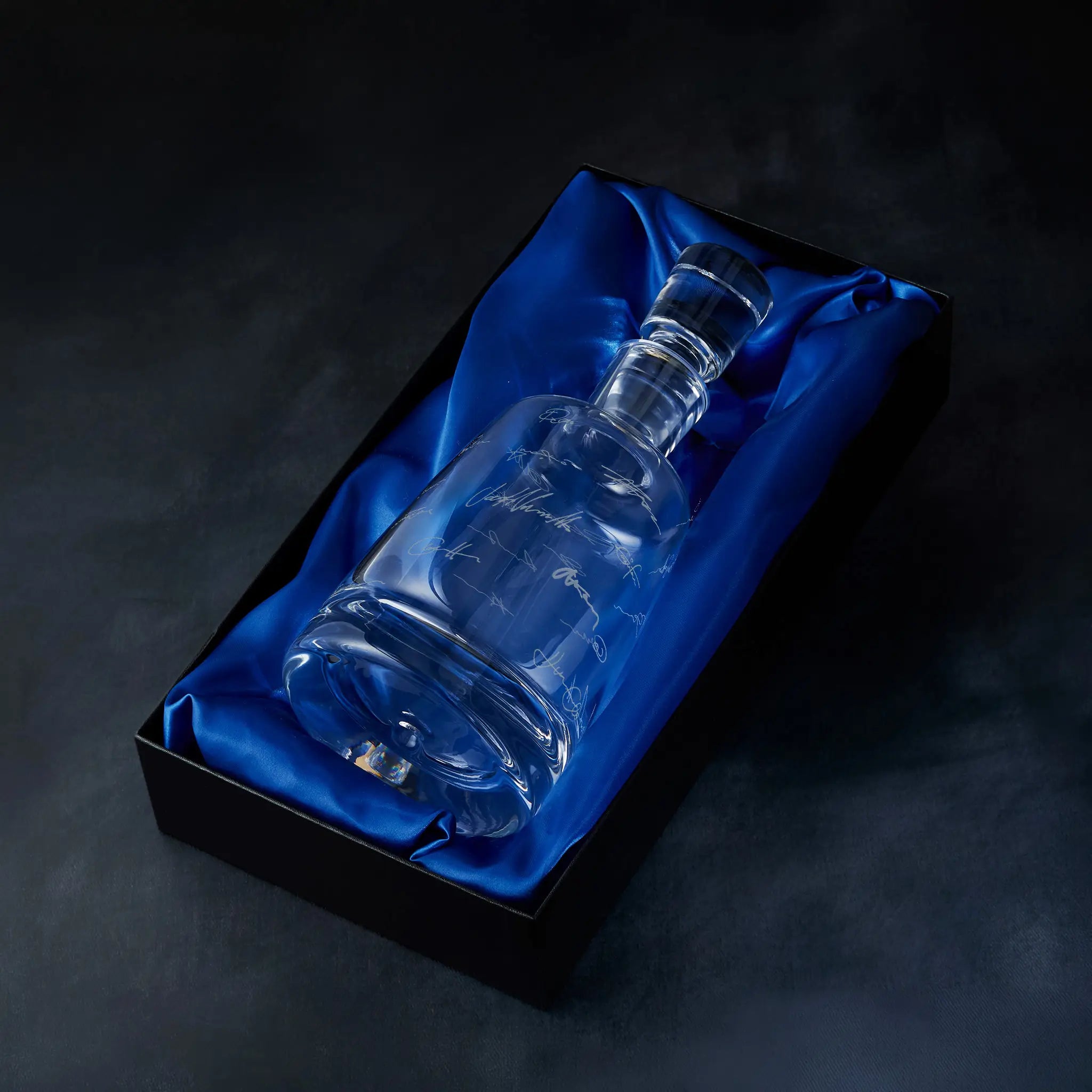 Engraved handritten signatures decanter presented in a satin-lined gift box, photographed on deep blue background