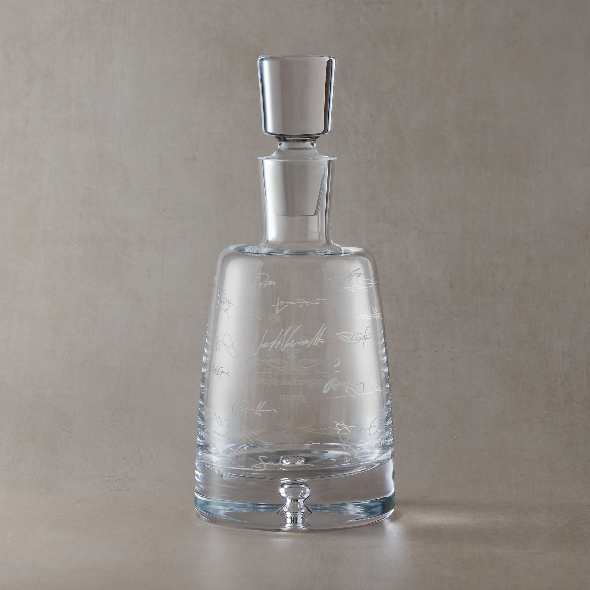 Engraved decanter with wraparound handwritten signatures on a beige background