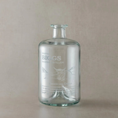 Engraved glass whisky bottle with a highland cow and personalised text on a beige background