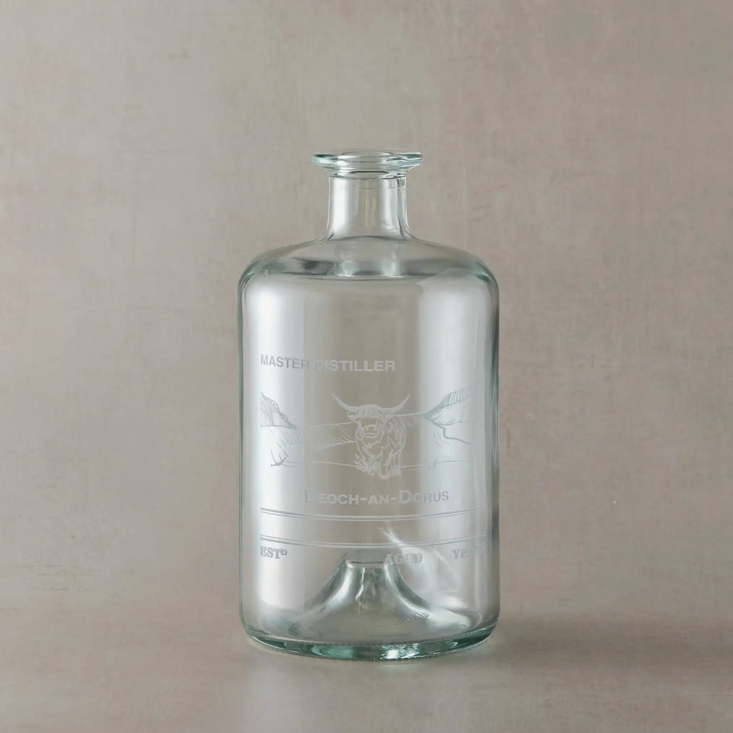 Apothecary decanter with engraved Highland Coo design on a beige background
