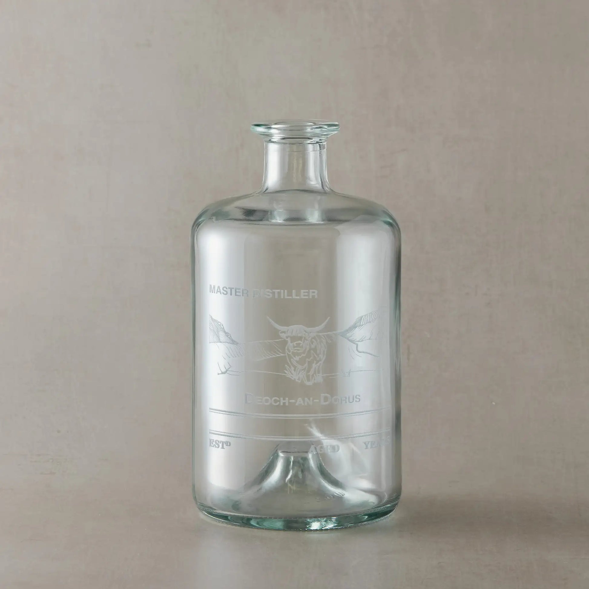 Apothecary decanter with engraved Highland Coo design on a beige background