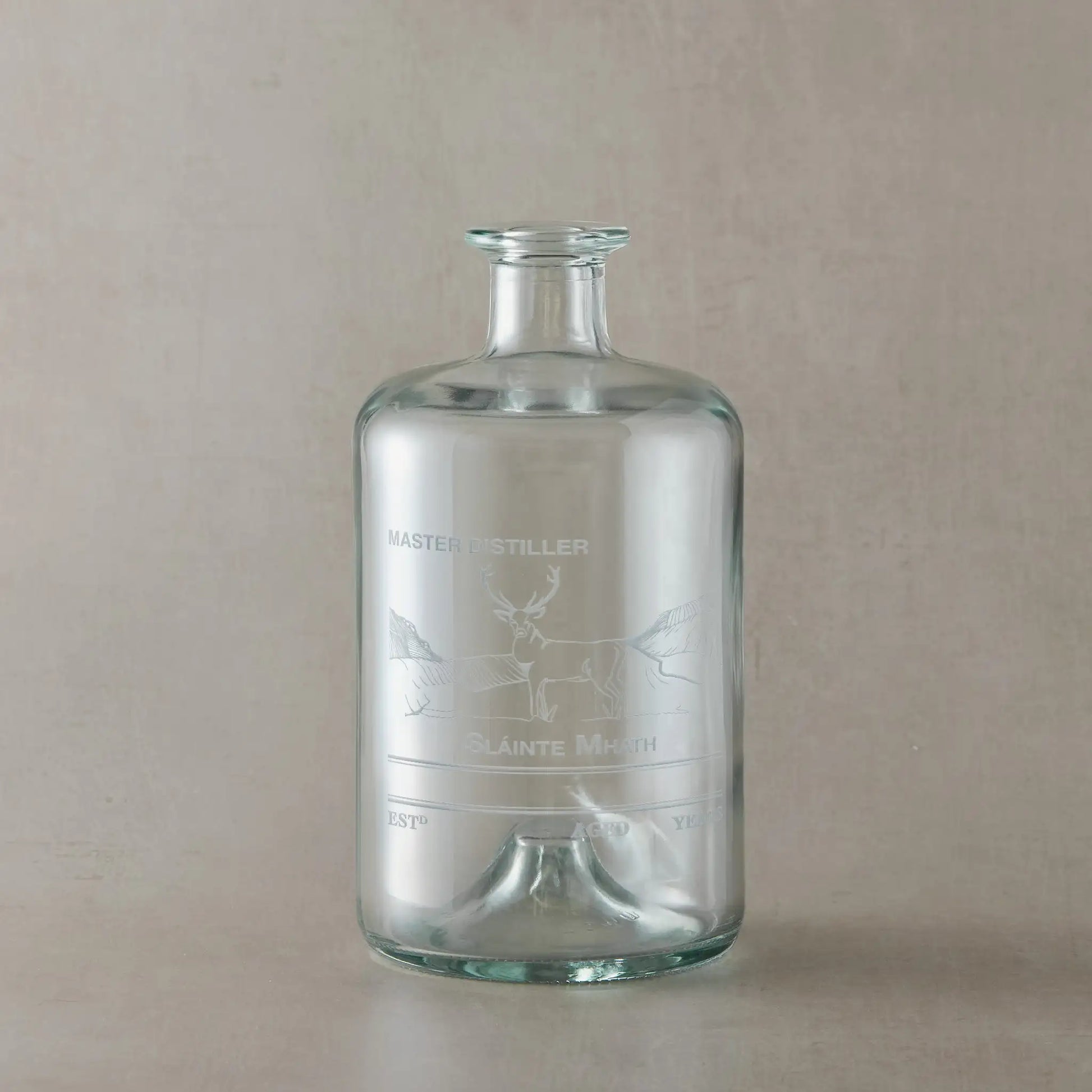 Glass apothecary decanter bottle with engraved stag design and personalisation areas on a beige background
