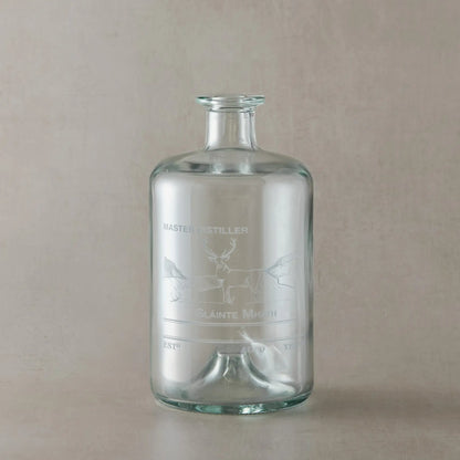 Glass apothecary decanter bottle with engraved stag design and personalisation areas on a beige background