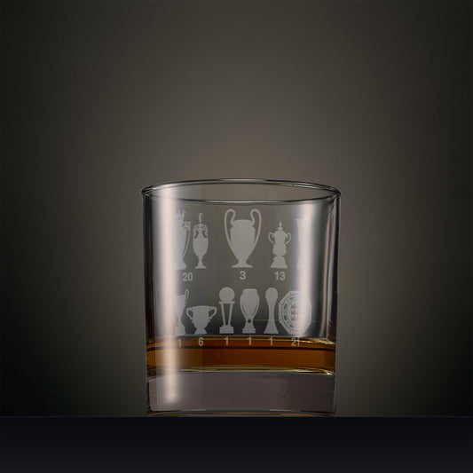 Engraved whisky glass featuring eleven trophy silhouettes with engraved numbers, shown on a dark background