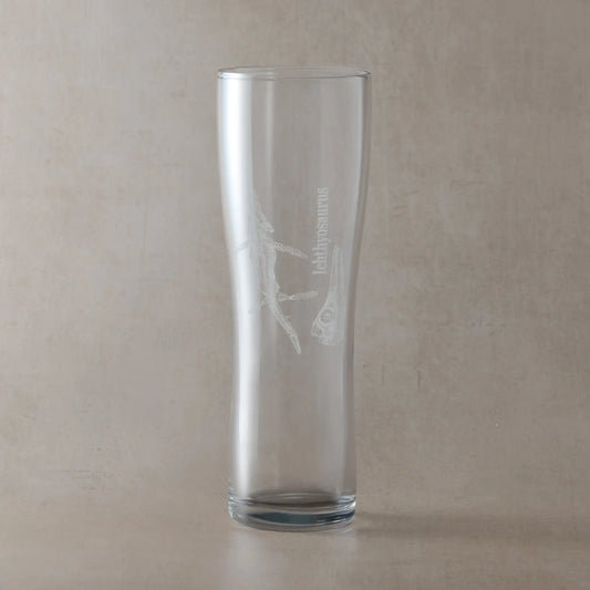 Pint glass featuring a detailed Ichthyosaur fossil engraving, photographed on a light background