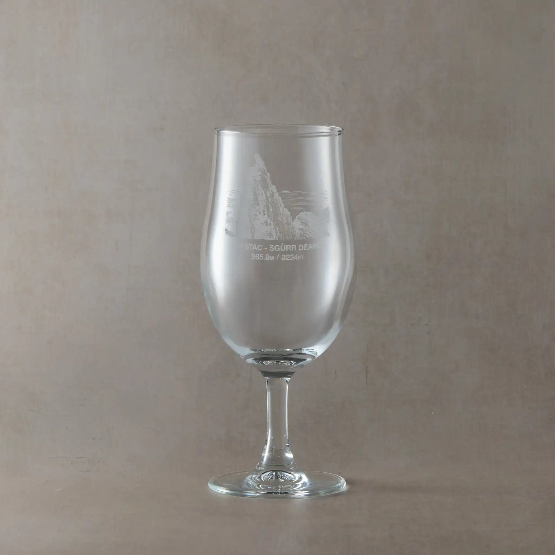 Stemmed Pint glass engraved with the Inaccessible Pinnacle, Sgurr Dearg, shown on a beige background