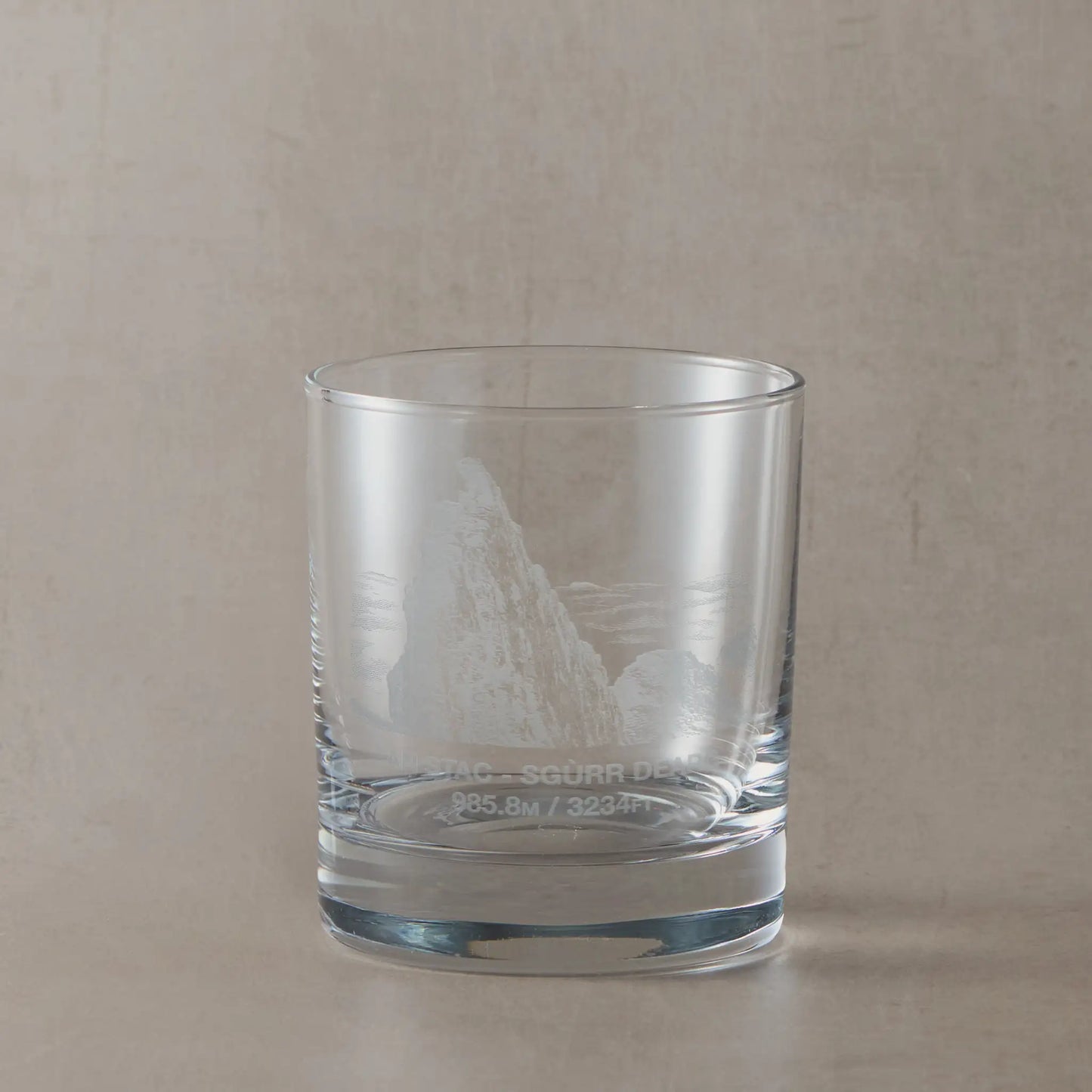 Whisky tumbler engraved with Sgurr Dearg and the Inaccessible Pinnacle, photographed on a beige surface