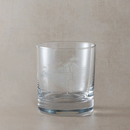 Clear whisky glass with engraved Isle of Wight map on a beige background