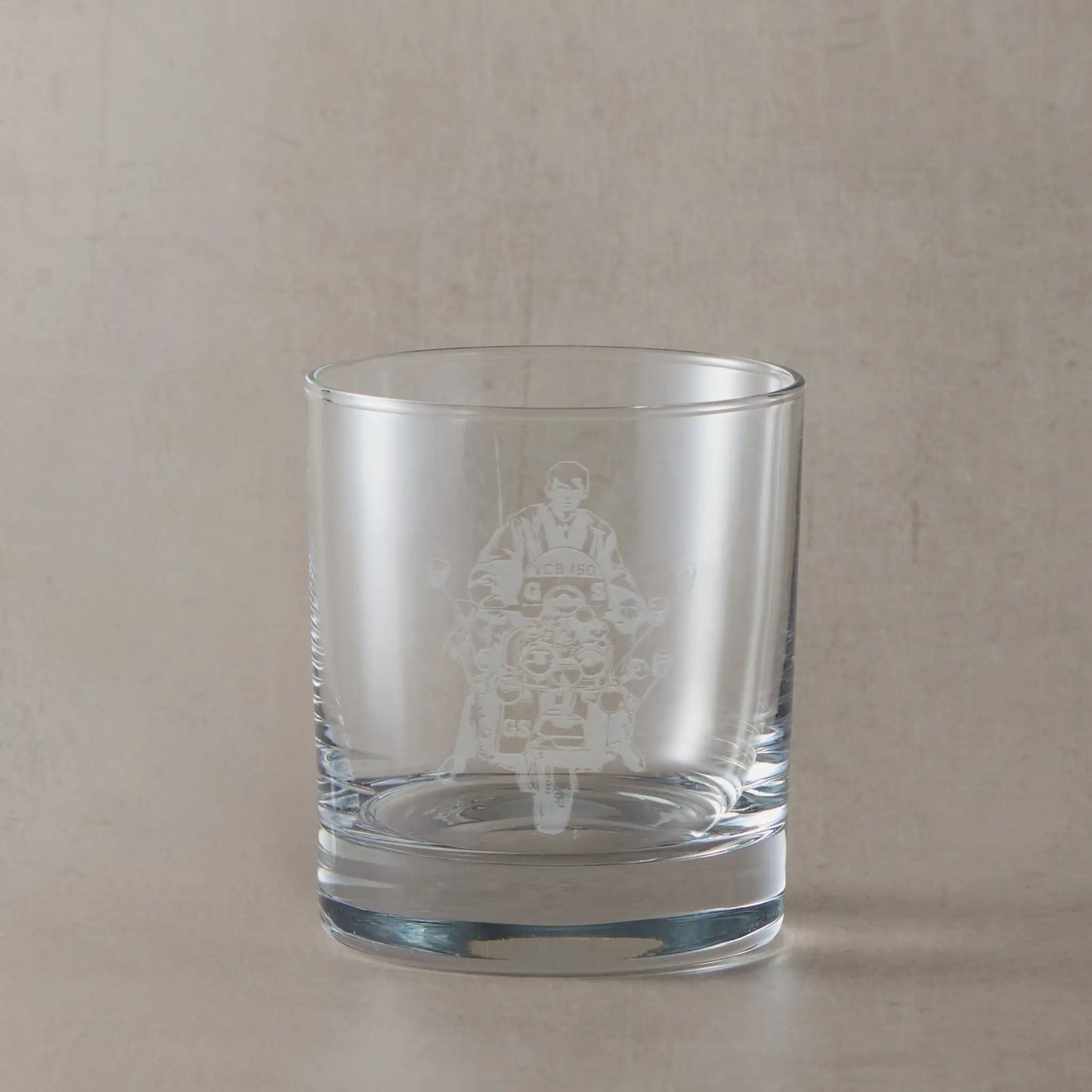 Whisky glass engraved with Jimmy and riding Ace Fsce's Vespa GS, shown on a beige background