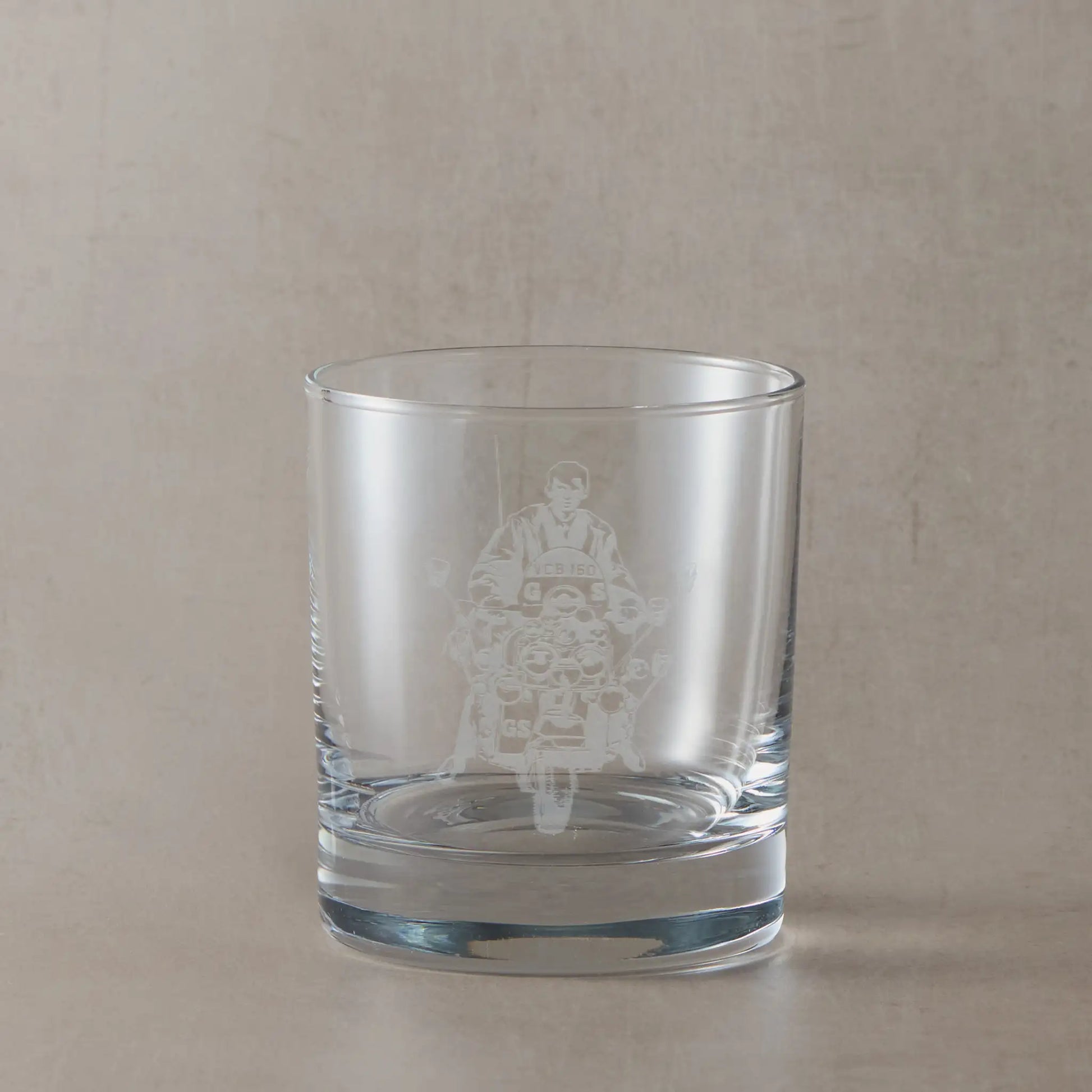 Whisky glass engraved with Jimmy and riding Ace Fsce's Vespa GS, shown on a beige background