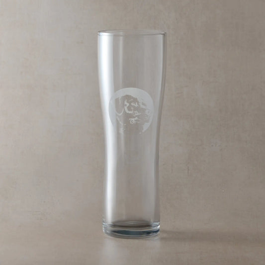 Pint glass engraved with a portrait of a Labrador shown against a neutral beige background.