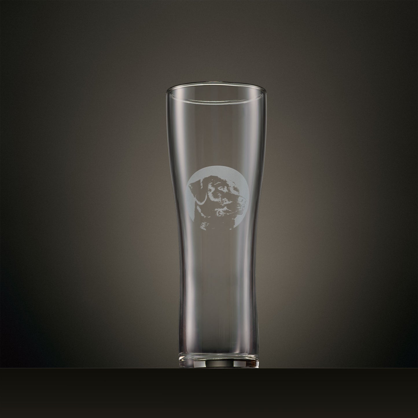 Engraved pint glass featuring a Labrador portrait set within a circular design, photographed on a dark studio background