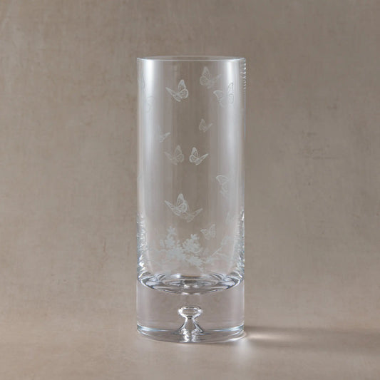 Clear glass vase with butterfly etching on a beige background