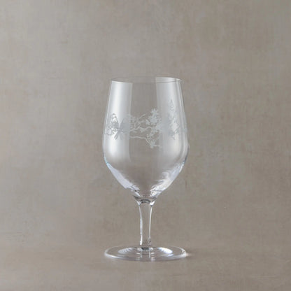 Mineral water glass with floral etching on a beige background