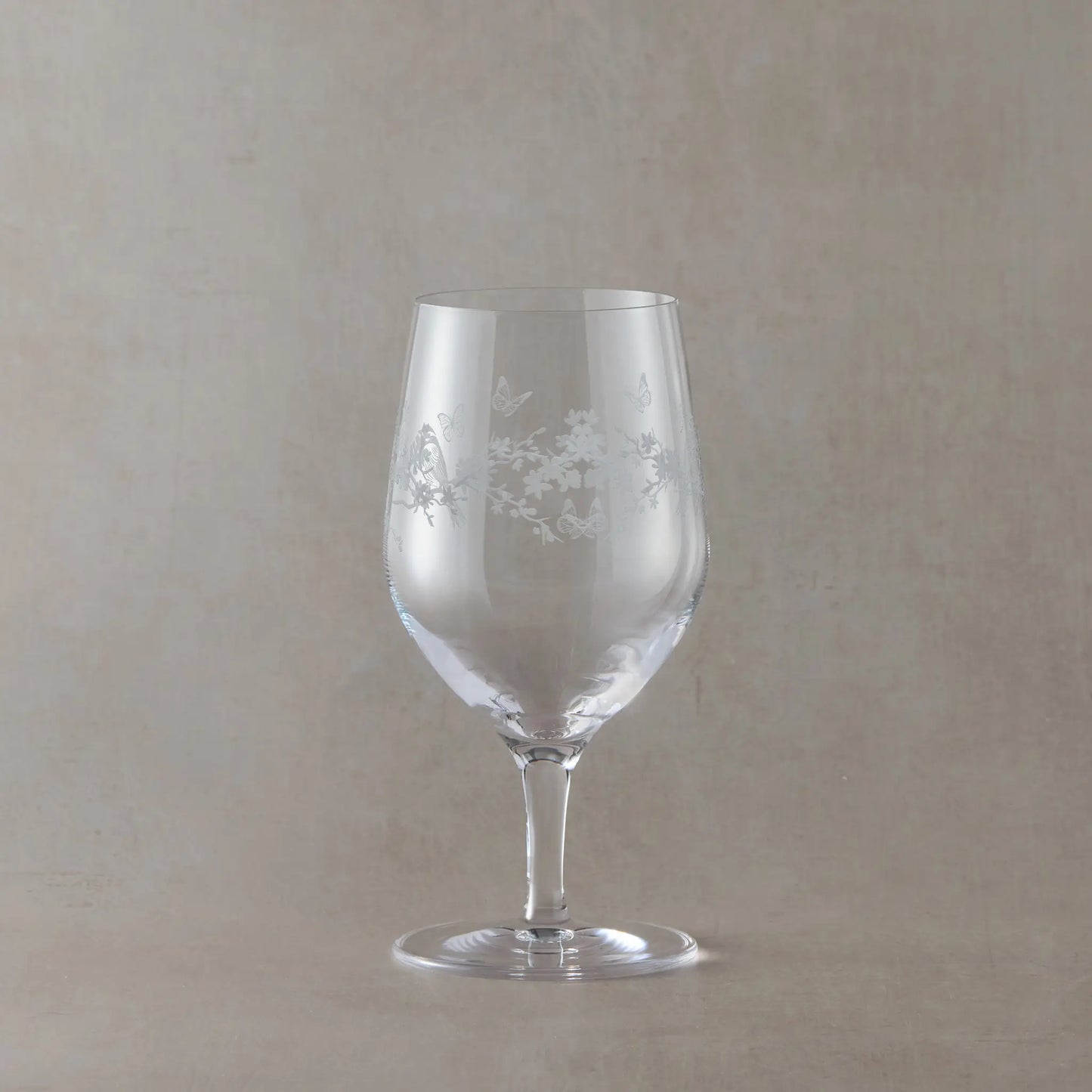 Mineral water glass with flowers, butterflies and garden birds etching on a beige background