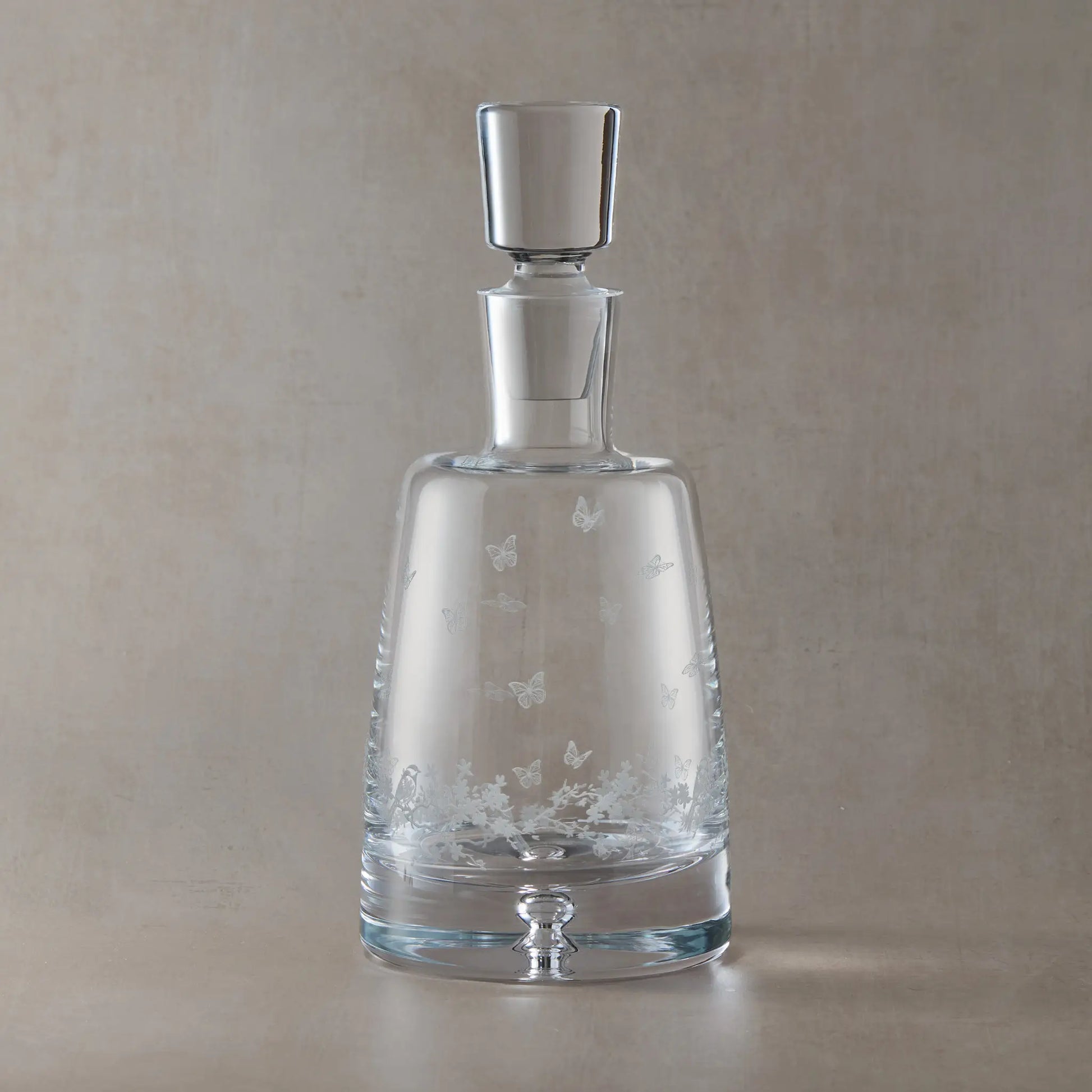 Engraved Le Jardin spirit decanter with wraparound floral garland, garden birds and butterflies on a beige background
