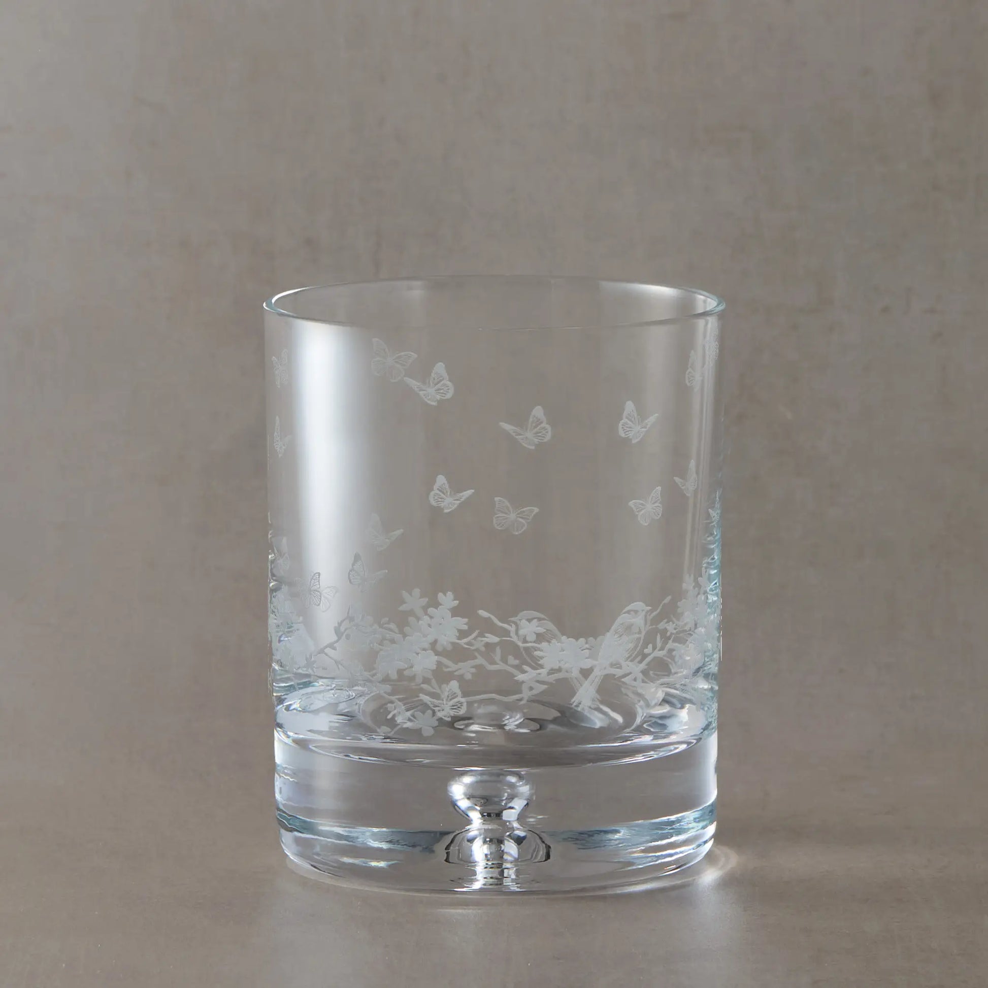 Engraved whisky glass featuring a wraparound floral garland, garden birds and butterflies