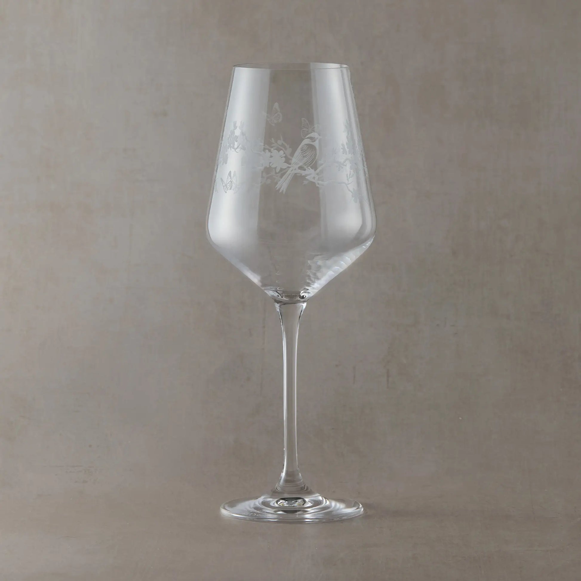 Clear wine glass engraved with a wraparound Le Jardin design featuring delicate butterflies and garden birds