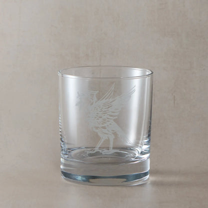 Whisky glass engraved with two Liverbirds, photographed on a beige background
