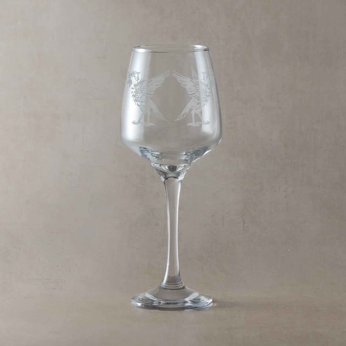 Clear wine glass engraved with two liverbirds, photographed on a light background
