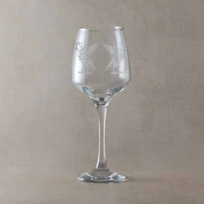 Clear wine glass engraved with two liverbirds, photographed on a light background