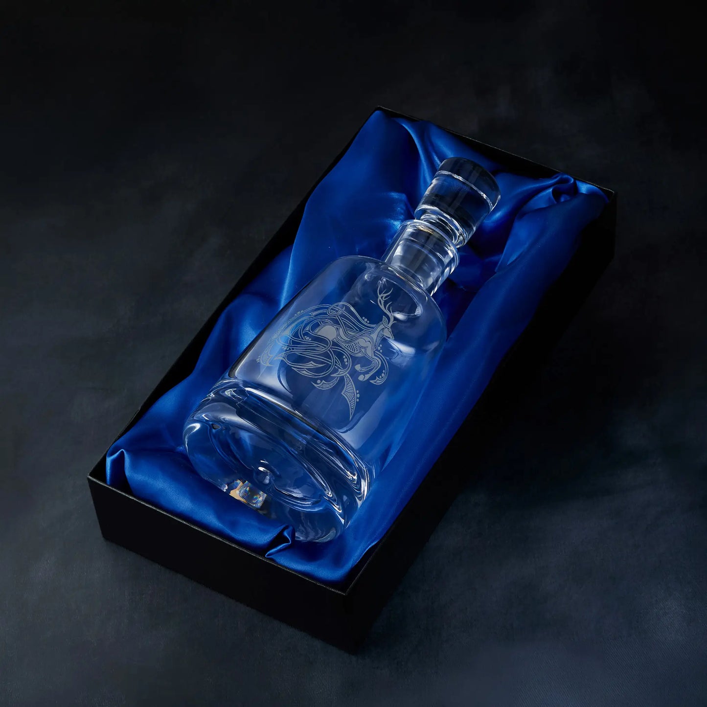 Engraved stag spirit decanter presented in a satin-lined gift box, photographed on deep blue background