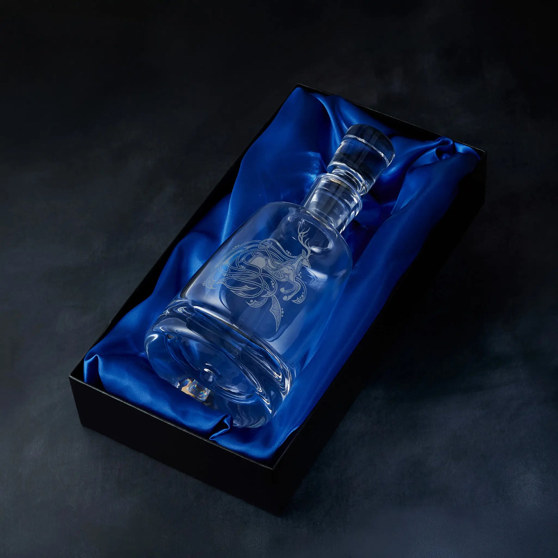Engraved stag spirit decanter presented in a satin-lined gift box, photographed on deep blue background