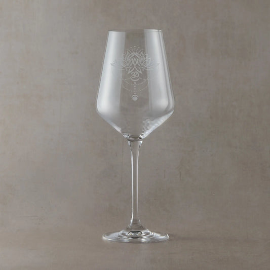 Hand-engraved Atelier wine glass featuring a lotus flower, Om symbol and moon phase design, sandblasted onto clear glass against a neutral beige studio background