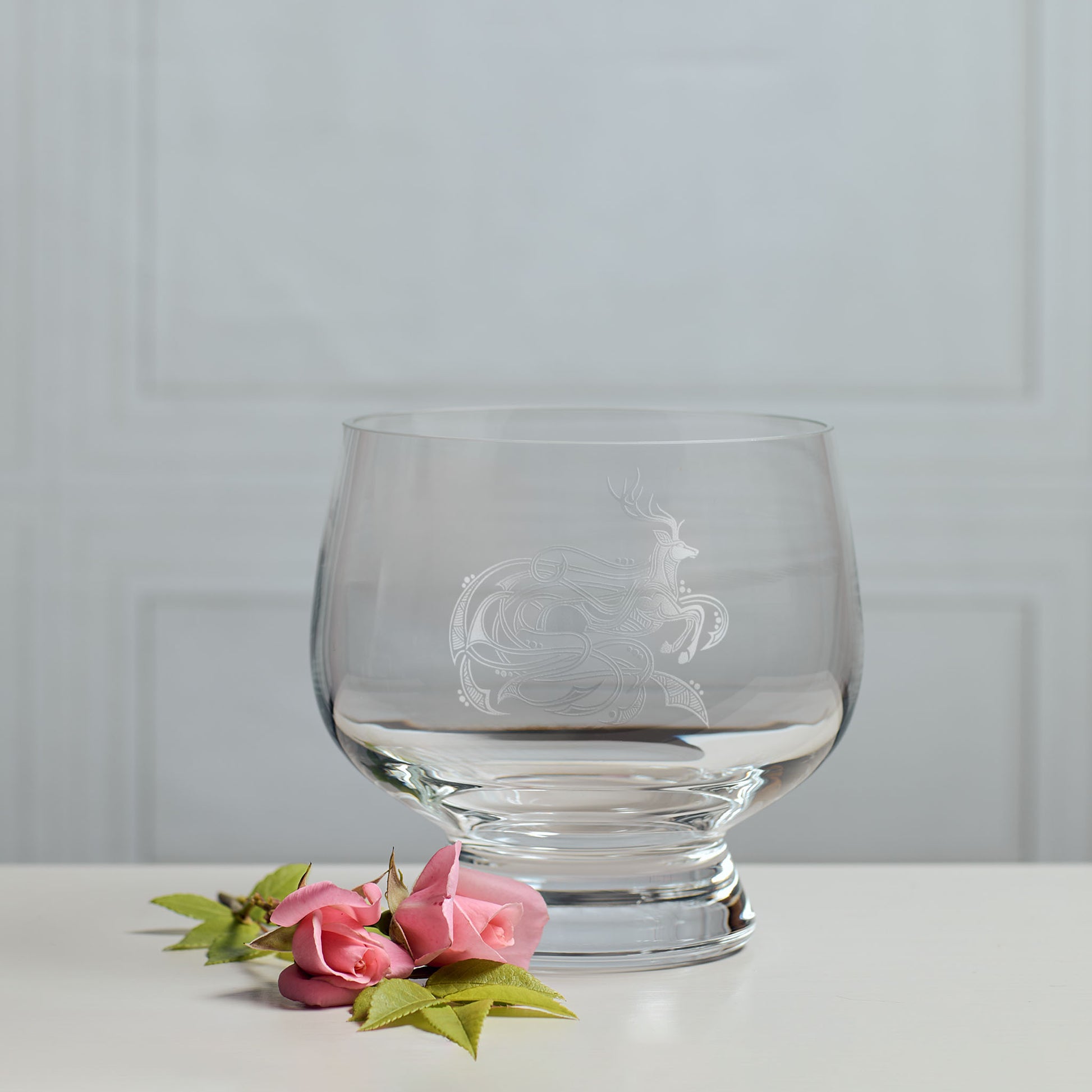 Presentation bowl engraved with a knotwork celtic stag design on a white surface with pink flowers