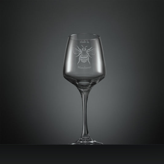 Engraved wine glass featuring a Manchester Bee and the words ‘Made in Manchester’ on a dark background