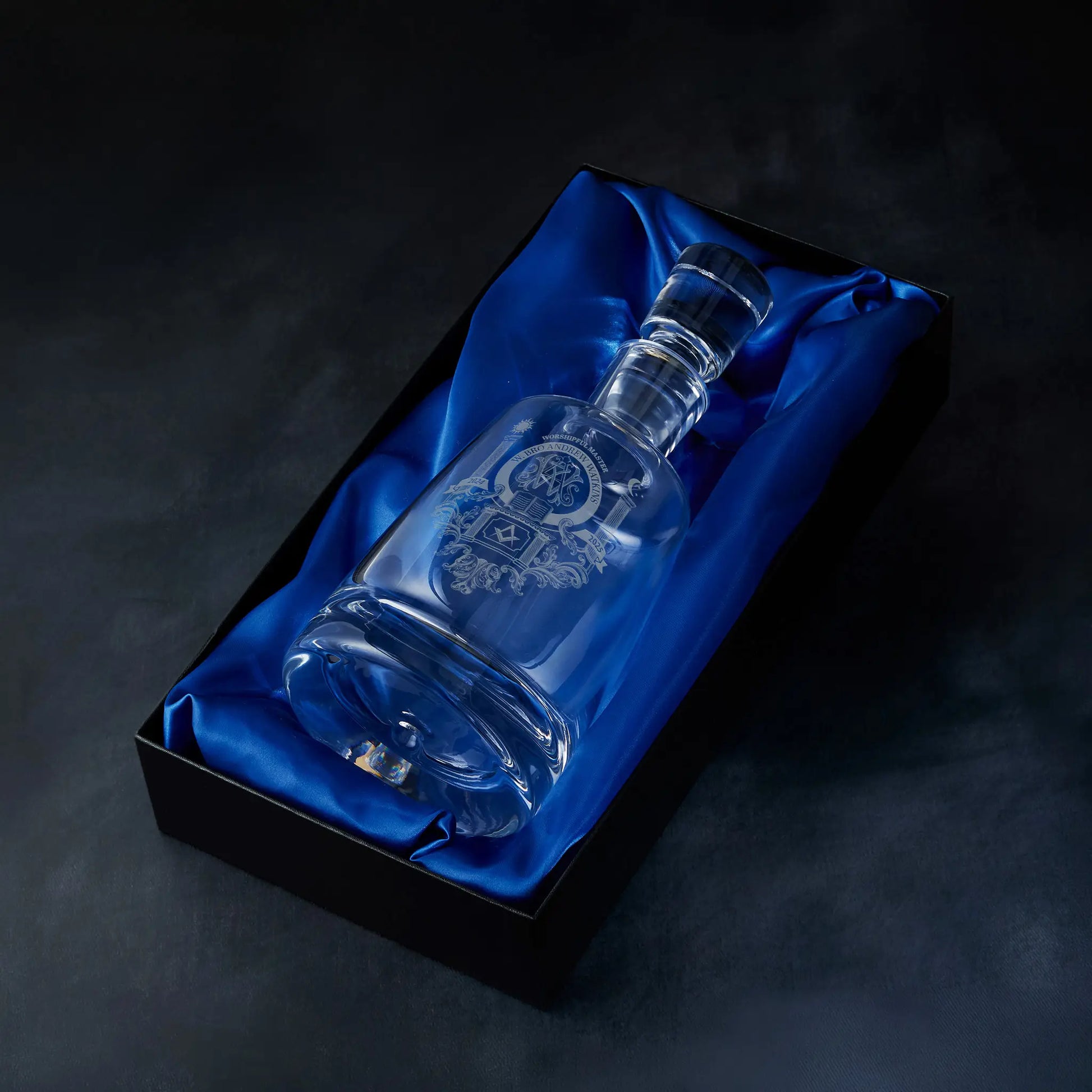 Engraved Masonic lodge crest spirit decanter presented in a satin-lined gift box, photographed on a deep blue background