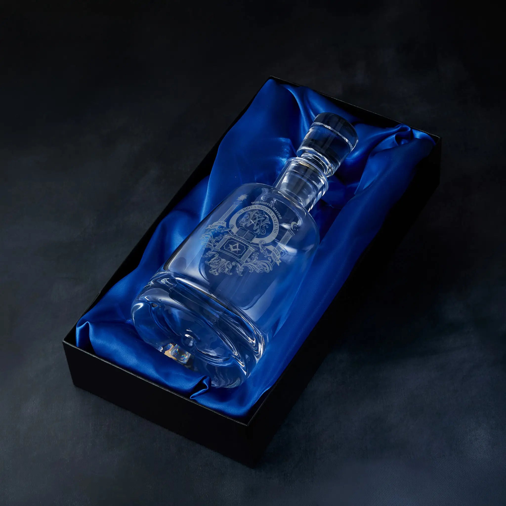 Engraved Masonic lodge crest spirit decanter presented in a satin-lined gift box, photographed on a deep blue background