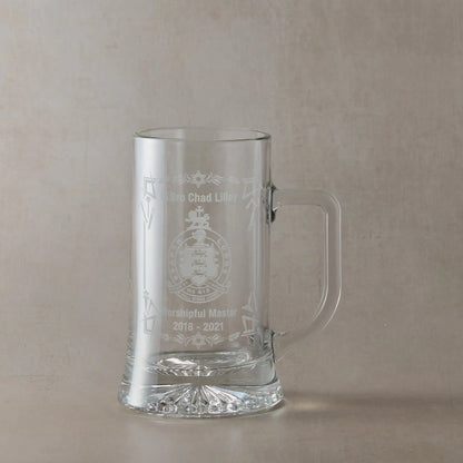 Engraved Masonic lodge crest tankard with right-handled glass, personalised with Worshipful Master name and dates, shown on a neutral beige studio background