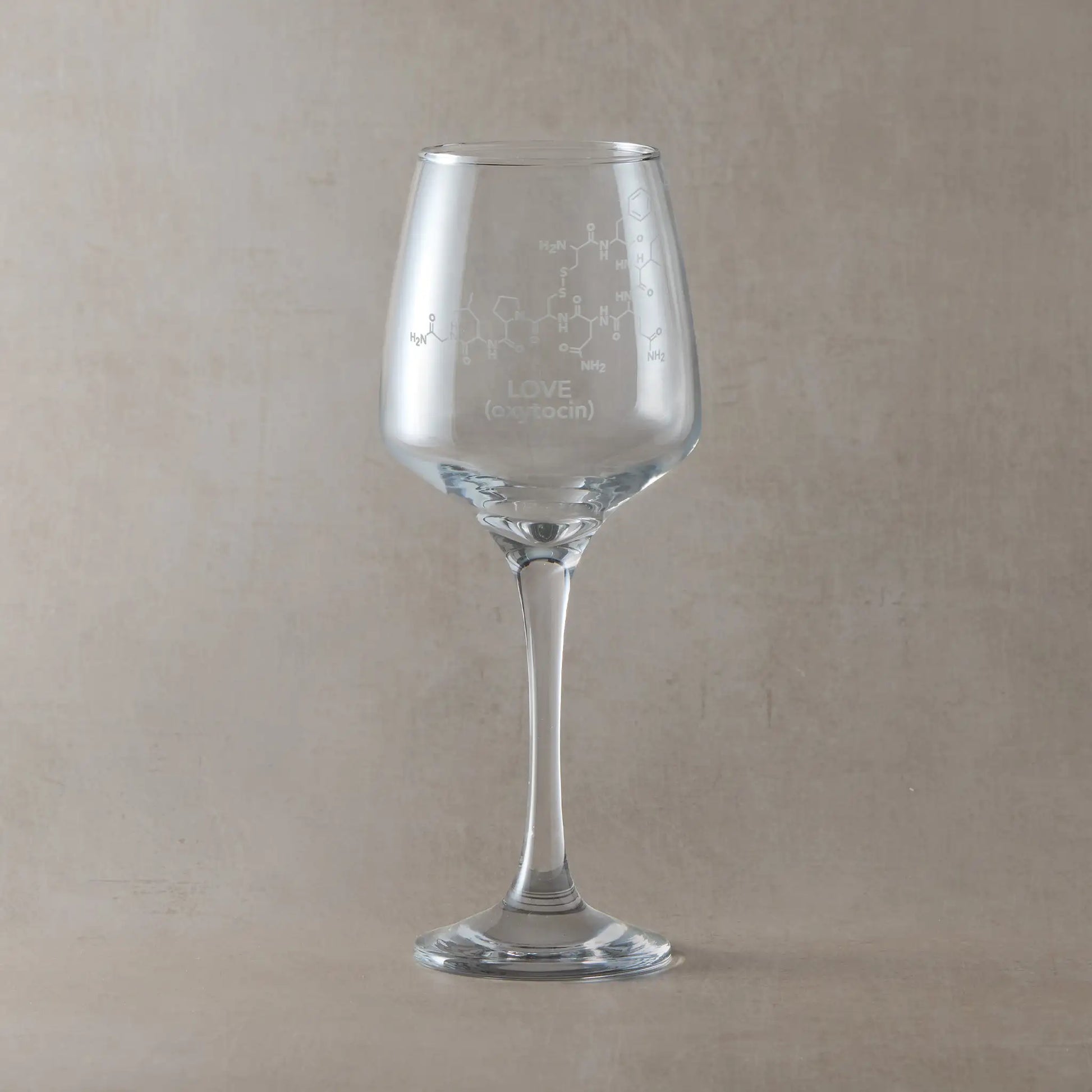 Wine glass with molecule engraved design and 'LOVE (oxytocin)' text, against a light background