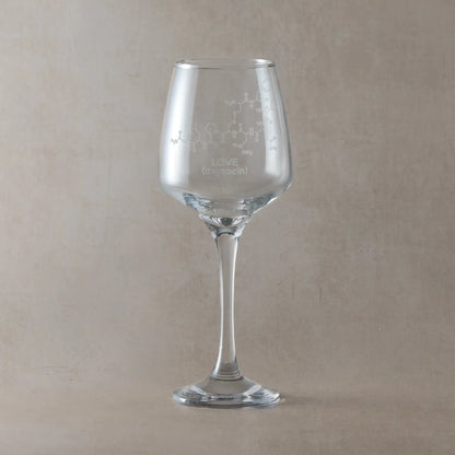 Wine glass with molecule engraved design and 'LOVE (oxytocin)' text, against a light background
