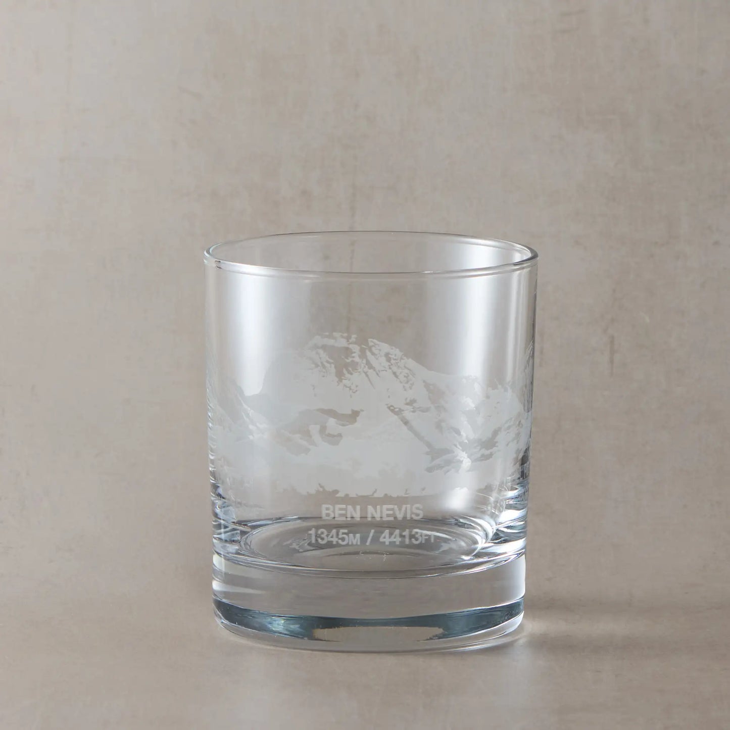 Whisky glass engraved with Ben Nevis, Scafell Pike and Snowdon, photographed on a studio background