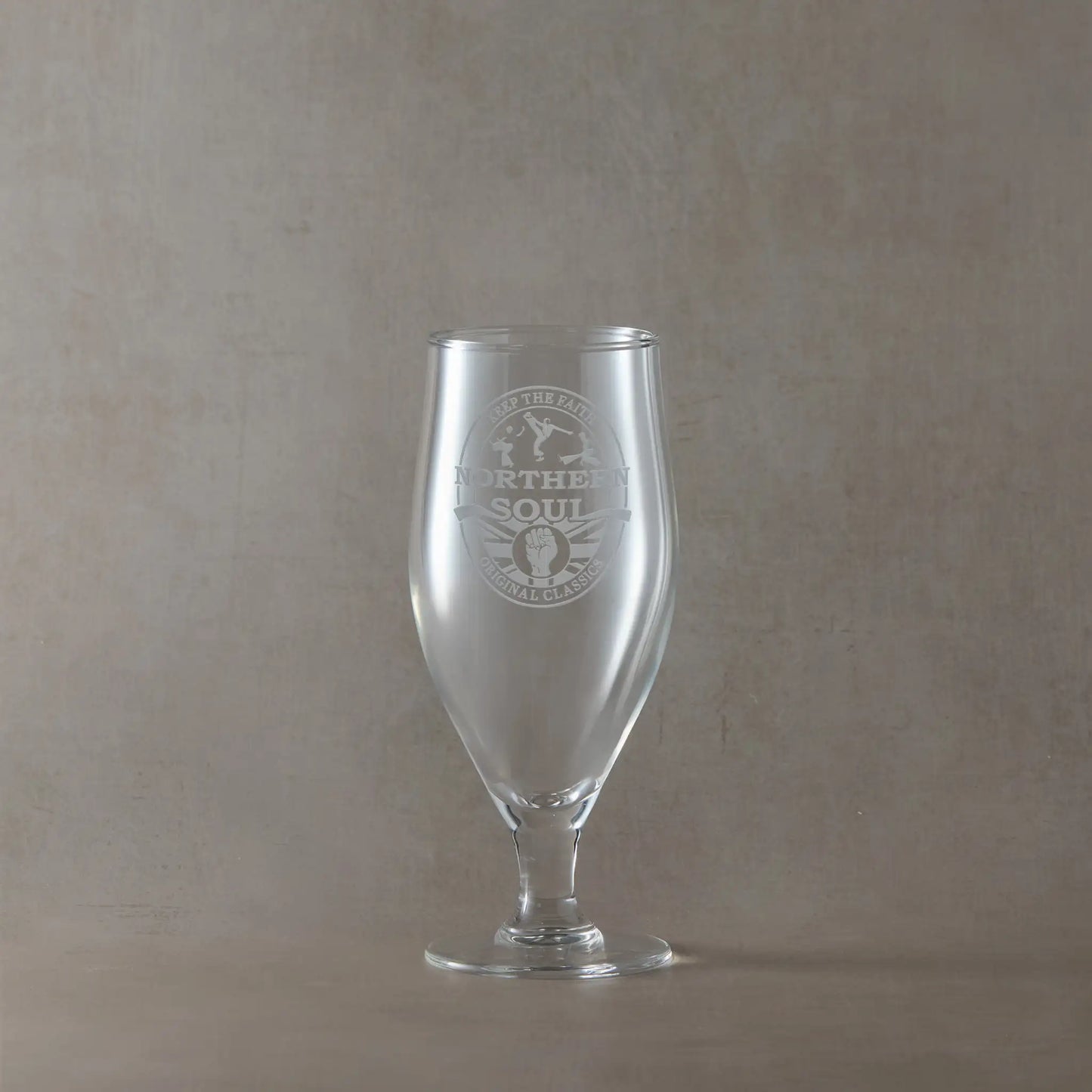 Stemmed chalice beer glass with engraved Northern Soul design on a beige background