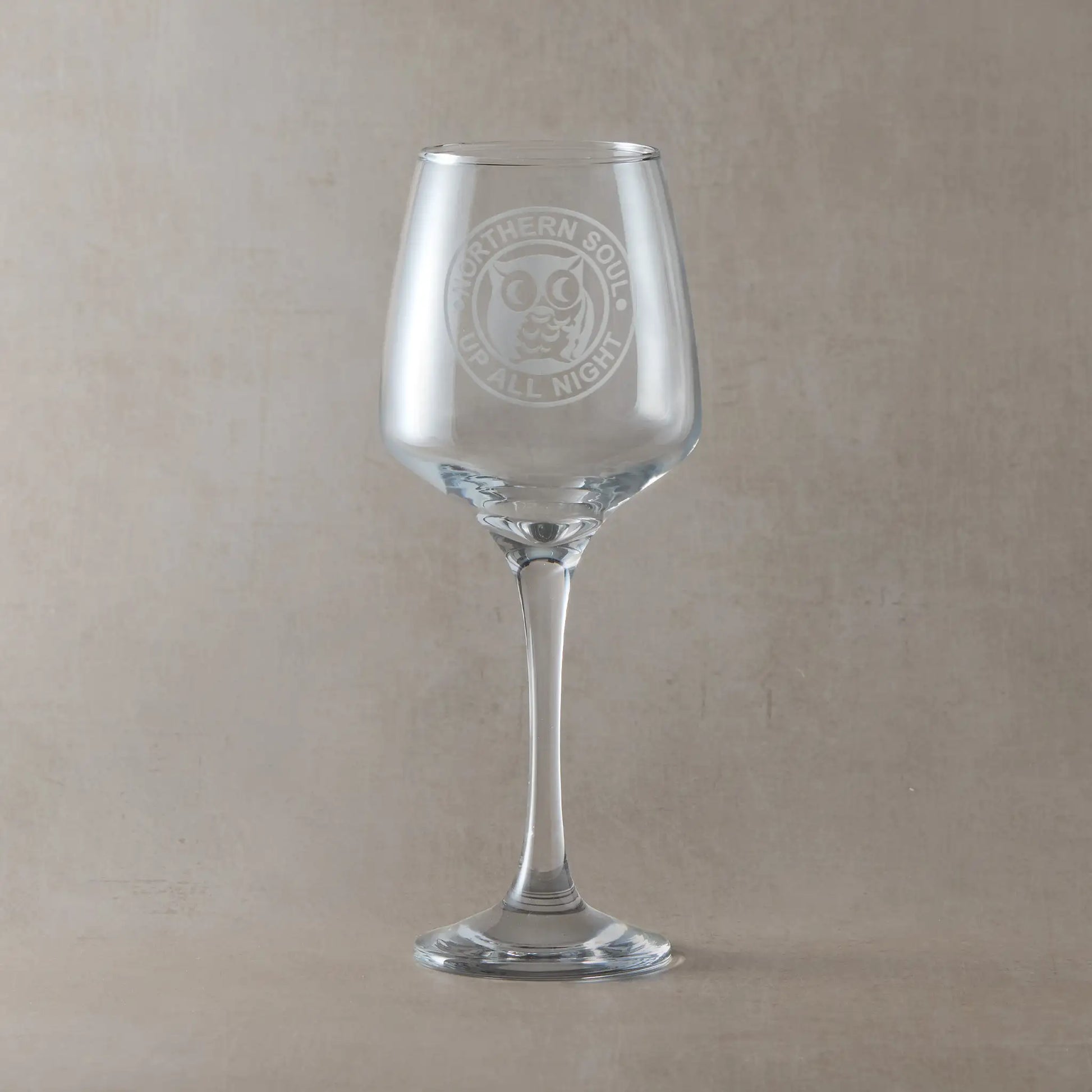 Wine glass with engraved Northern Soul night owl design on a beige background