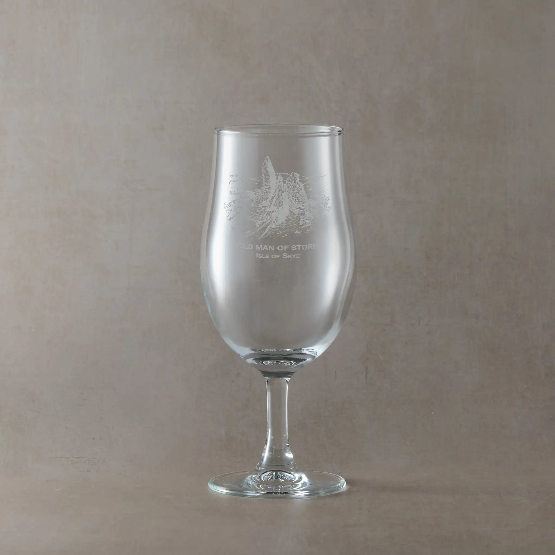 Stemmed beer pint glass engraved with Old Man of Storr design shown on beige background