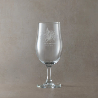 Stemmed beer pint glass engraved with Old Man of Storr design shown on beige background