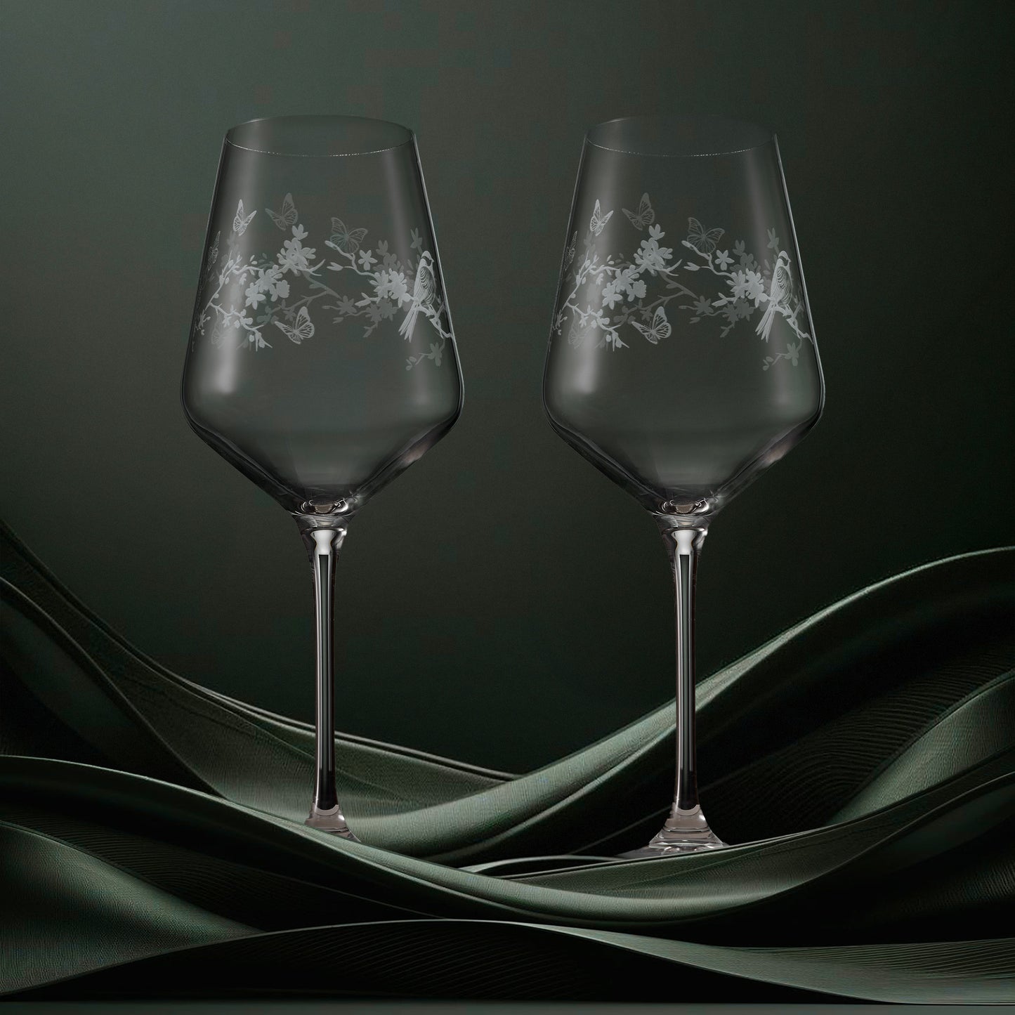 Two clear wine glasses featuring garden birds, blossom and butterflies in a wraparound design