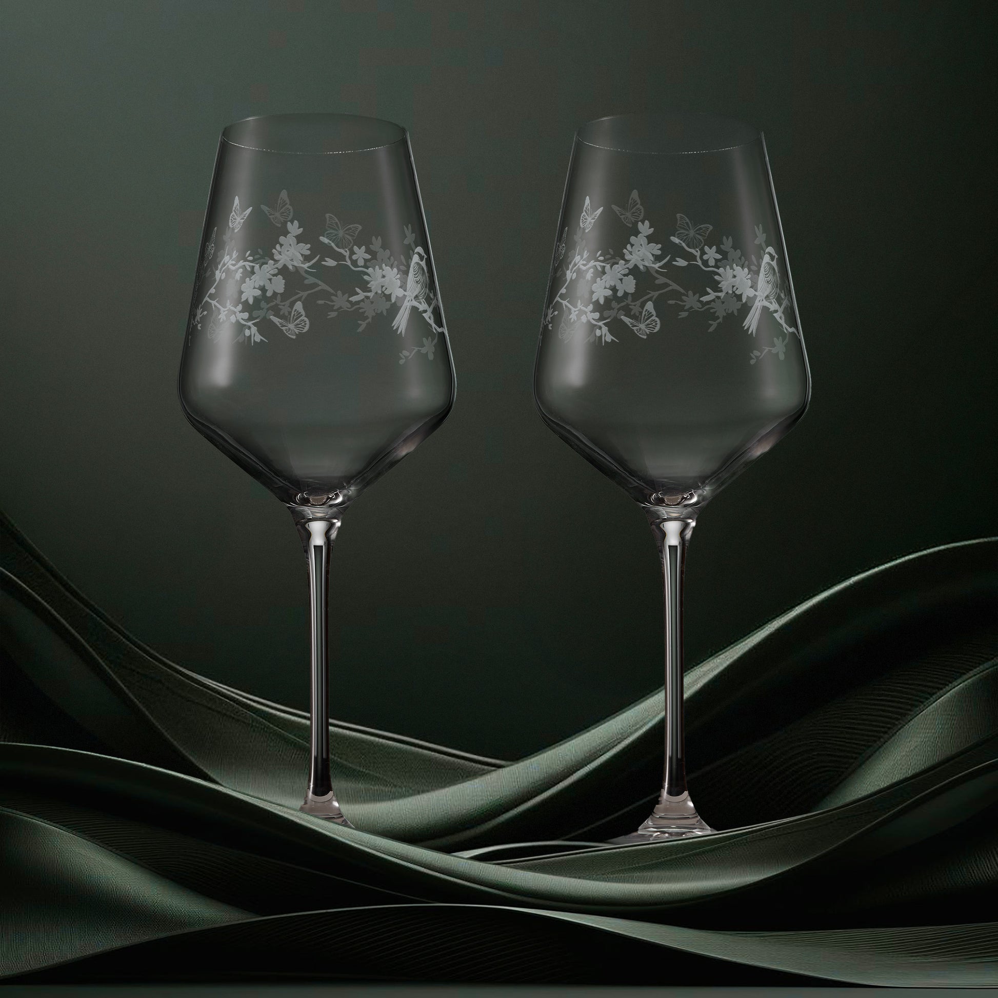 Two clear wine glasses featuring garden birds, blossom and butterflies in a wraparound design