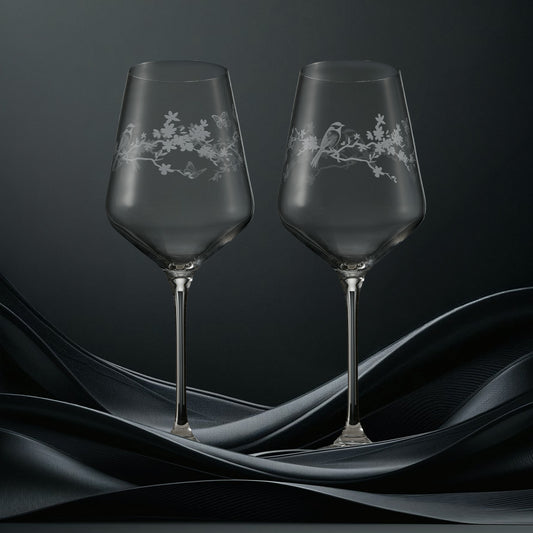 Two clear wine glasses featuring garden birds, blossom and butterflies in a wraparound design