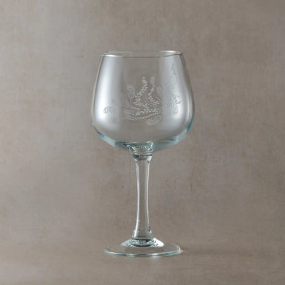 Engraved gin glass featuring a flowing peacock with feathers and trailing leaves, inspired by Pittencrieff Park’s flora
