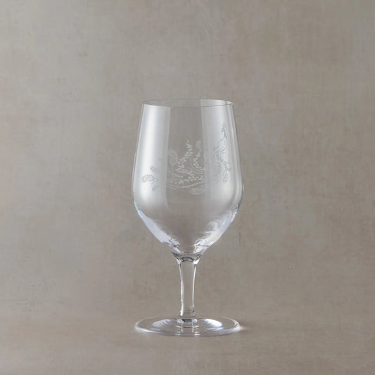 Engraved mineral water glass featuring peacock design with trailing feathers, shown on a beige background