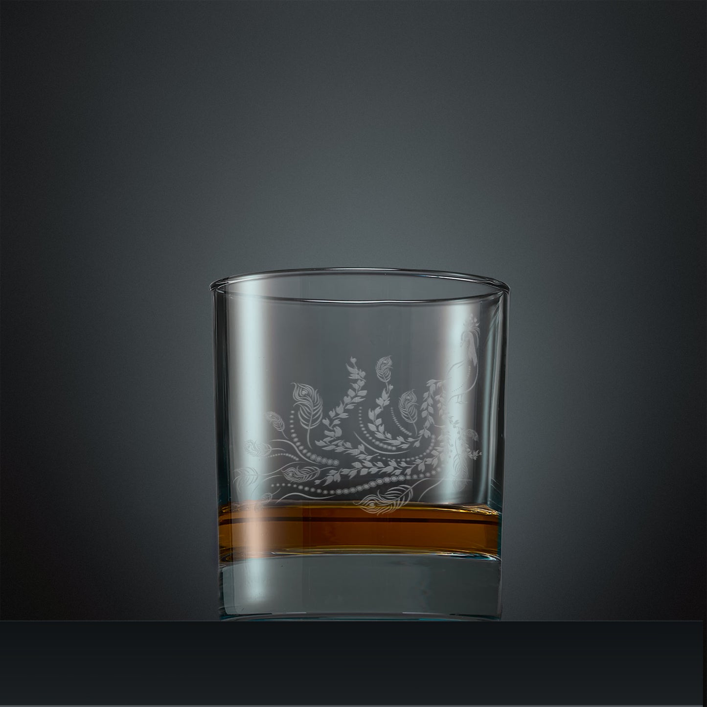 Engraved whisky glass with a peacock, trailing leaves and feathers design