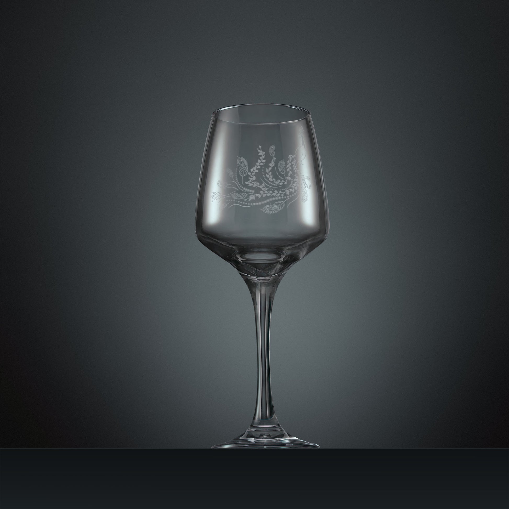 Engraved wine glass with a peacock, trailing leaves and feathers design